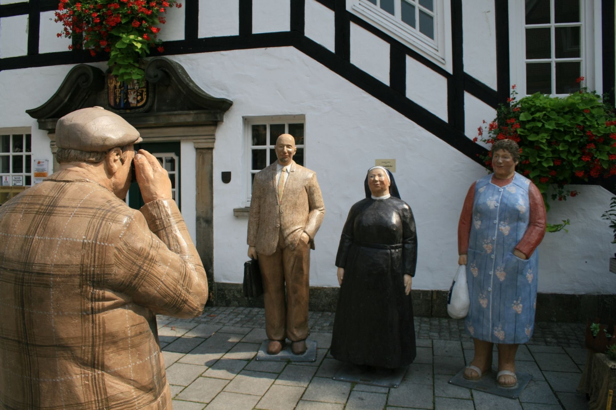 Die so genannten Alltagsmenschen vor dem Rathaus. Die Figurengruppe, geschaffen von der Künstlerin Christel Lechner, zeigt einen Geschäftsmann, eine Nonne und eine Hausfrau, die für einen Fotografen posieren.