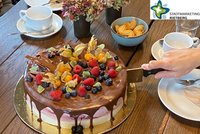 Eine mit Früchten dekorierte Torte, die gerade angeschnitten wird.
