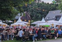 Blick aufs Weinfest 2024 mit vielen Menschen, die an Bierzeltgarnituren sitzen. Im Hintergrund die Pagoden-Zelte.