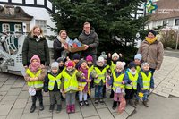 Kindergartenkinder mit Deko in der Hand vor dem großen Weihnachtsbaum, hinten die Erzieherinnen und Bürgermeister Andreas Sunder.