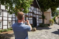 Zu sehen ist ein Mann von hinten, der die Häuser in der Klosterstraße fotografiert.