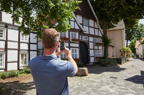 Zu sehen ist ein Mann von hinten, der die Häuser in der Klosterstraße fotografiert.