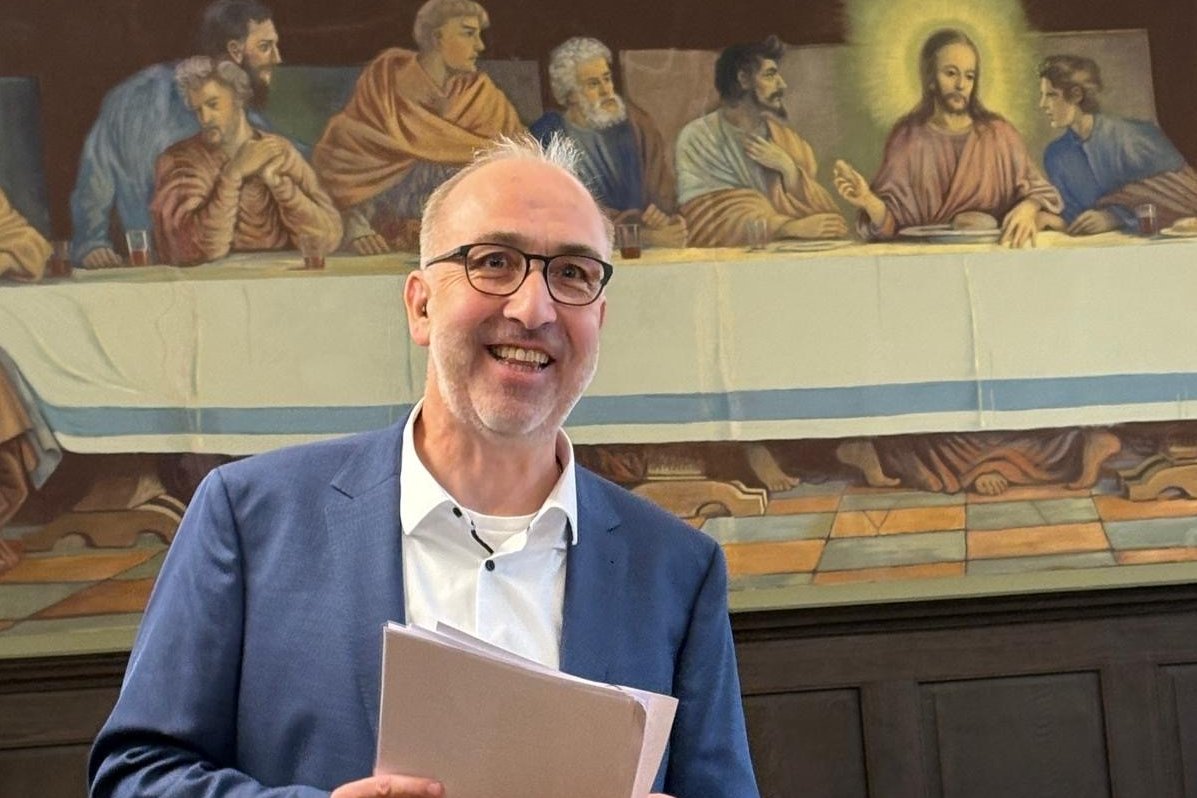 Gästeführer Dirk Rübbelke steht mit Manuskript in der Hand vor dem Gemälde "Letztes Abendmahl" im Refektorium