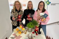 Die Mitarbeiterinnen der Touristikinformation stehen hinter einem gedeckten Tisch, in der Gand Weingläser, Mini-Rietis und Flyer.