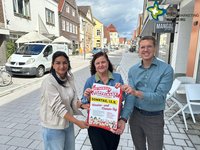 Die genannten Personen stehen auf der Rathausstraße und halten ein Plakat hoch. Sie schauen in die Kamera.