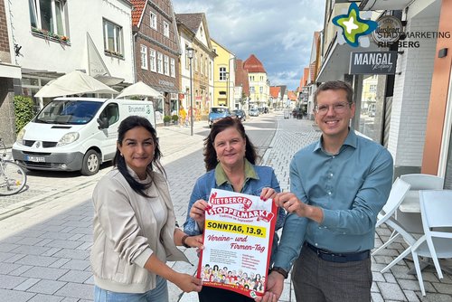 Die genannten Personen stehen auf der Rathausstraße und halten ein Plakat hoch. Sie schauen in die Kamera.