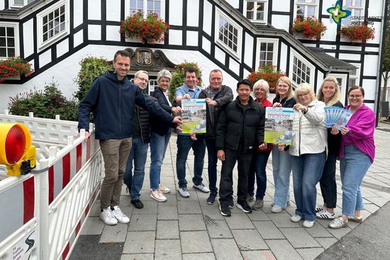 Teilnehmer der Aktion mit Plakaten und Gutscheinen vor dem Rathaus. Links ist eine Baustellen-Absperrung zu sehen.