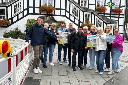 Teilnehmer der Aktion mit Plakaten und Gutscheinen vor dem Rathaus. Links ist eine Baustellen-Absperrung zu sehen.