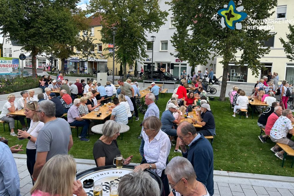 Baustellenfest im August 2025: Menschen sitzen auf dem neuen Platz am Nordtor an Bierzelttischen, im Hintergrund Musiker Patrick Lück.